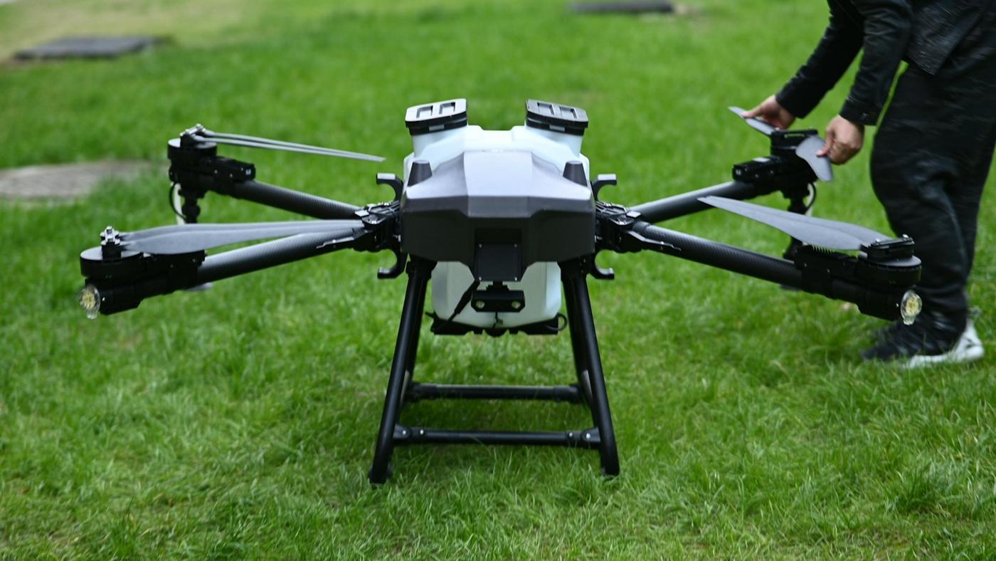 Operator preparing a spraying drone on grass